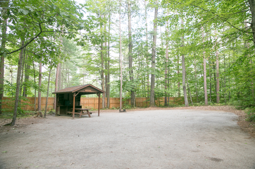 Dining Shelter campsite includes a wooden canopy over the picnic table, kitchen workspace, and ample shelves for storing cooking equipment and canned goods.